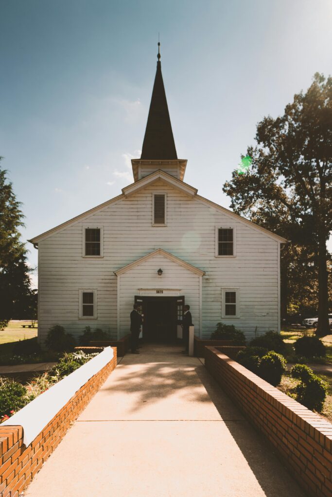 A picturesque chapel with a steeple and wooden architecture set in the countryside under clear skies. Marketing Easter Sunday